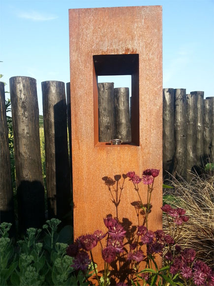 An oil lantern made from rusted metal is softened by planting and is perfect garden focal points