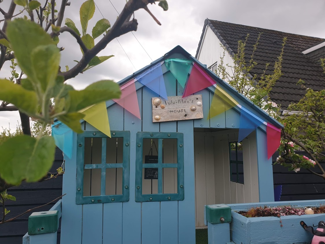 The playhouse bedecked in its upcycled garden bunting