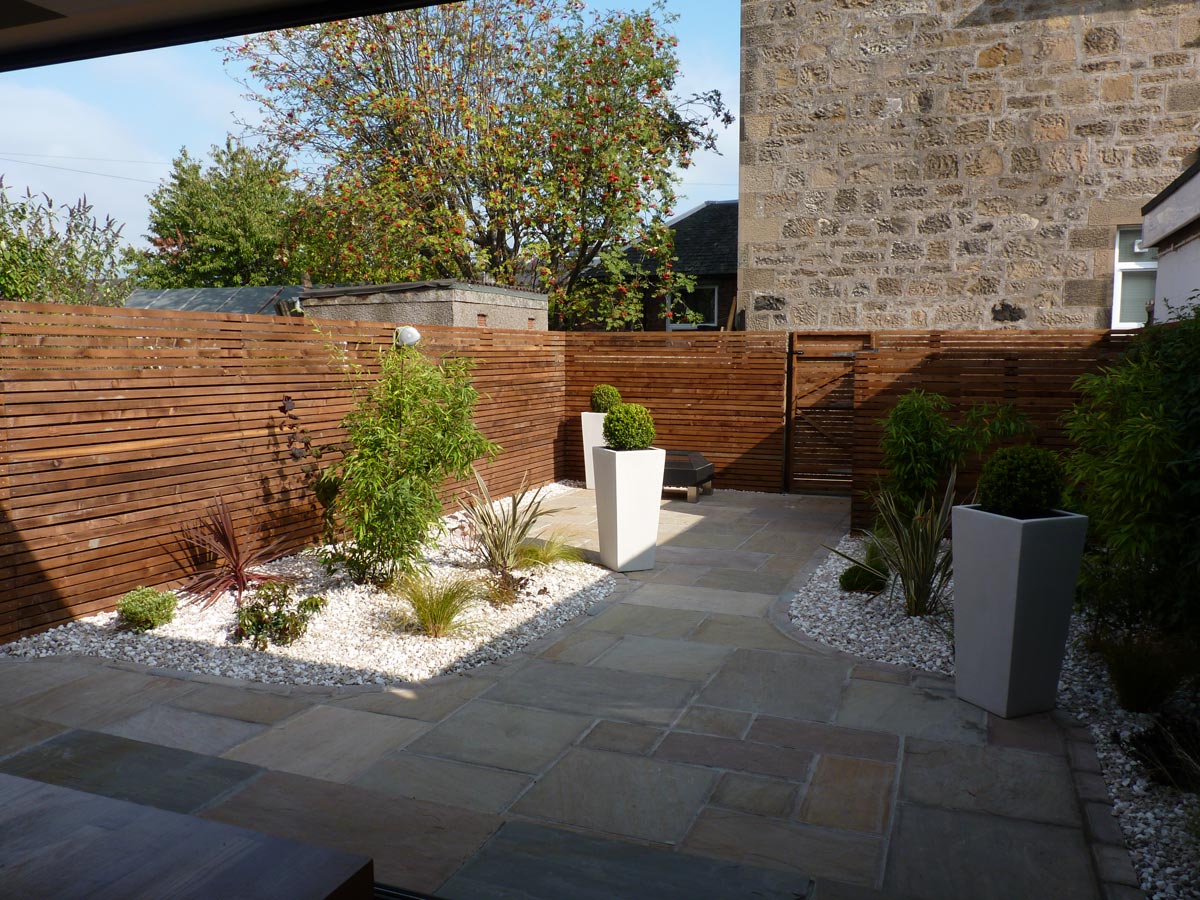 Tall stone planters create a contemporary look to tie in with the garden design and new house extension