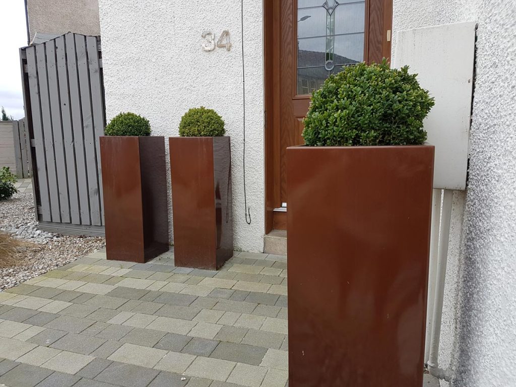Rectangular copper planters create a warm welcome