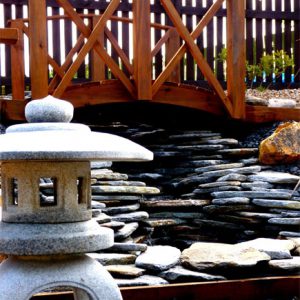 A Japanese lantern, water feature and koi bridge set the mood in this garden