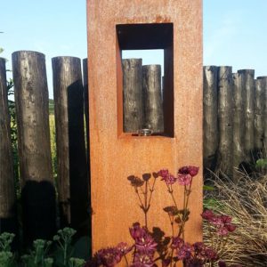 An oil lantern made from rusted metal is softened by planting