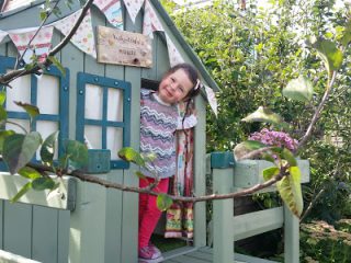 The new playhouse is tucked in the border between two apple trees