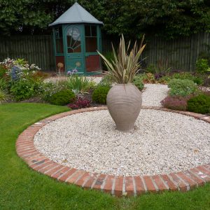 Feature pot in a gravel circle with the Art Deco summerhouse beyond
